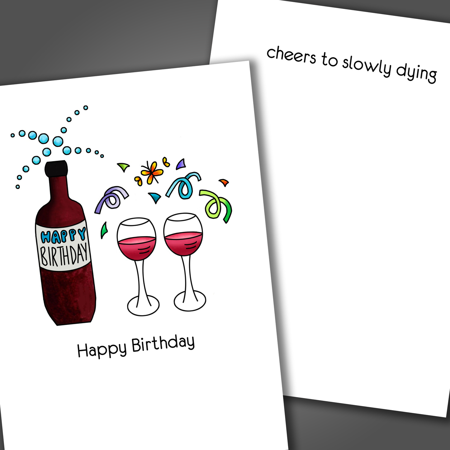 Funny happy birthday card with bottle of wine and two wine glasses on front of card. Inside the card is a funny joke that says cheers to slowly dying!